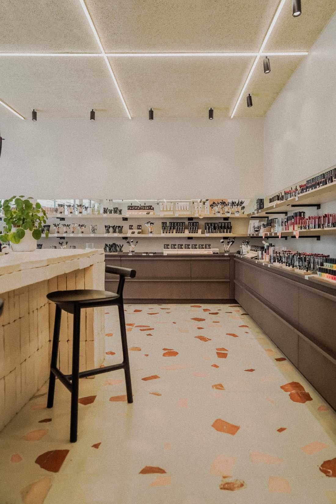 Enduit à la chaux et plafond en bois souligné de lignes lumineuses au-dessus des présentoirs de la boutique