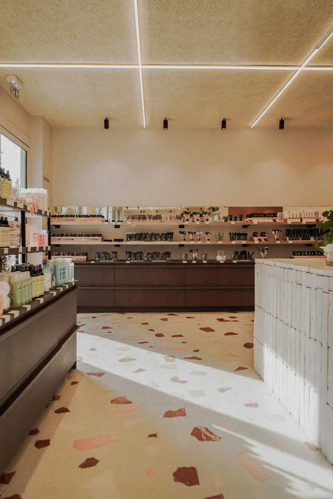 Sol en terrazzo et comptoir en briques blanchies dans la boutique de cosmétiques Avril